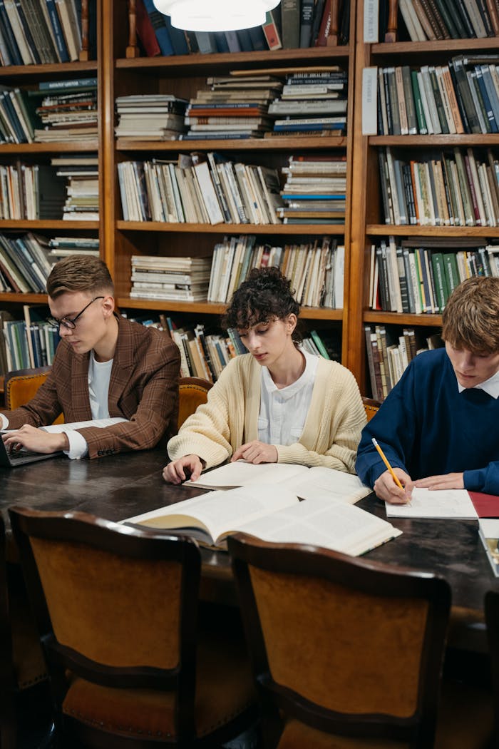 services-01 Students focused on studying in a university library filled with bookshelves.